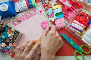 Hands using scrapbooking tools with the word lovely