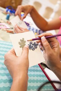 Ladies scrapbooking, considering ribbons and trims on photograph.